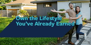 A couple standing outside their home with the text 'Own the lifestyle you've already earned' 