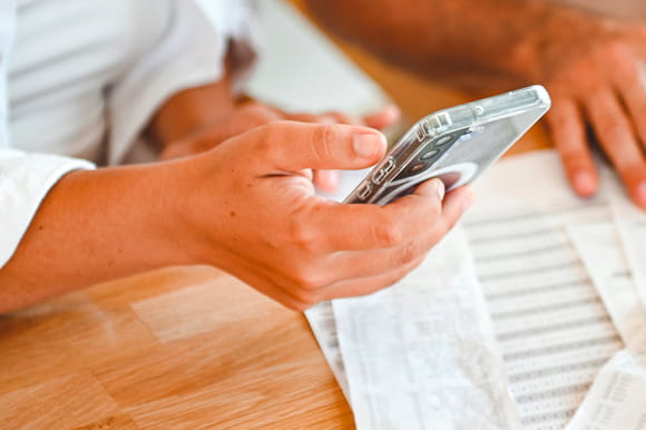 Hands typing in phone to handle then financial affairs of a family member.