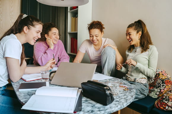 Four teens together at the dinner table talking about money