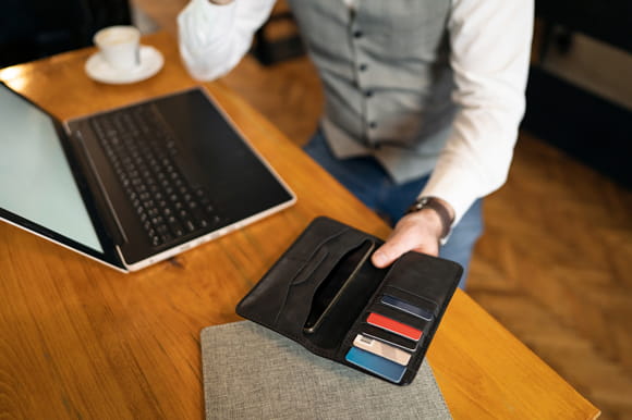 A person holding their wallet open showing credit cards